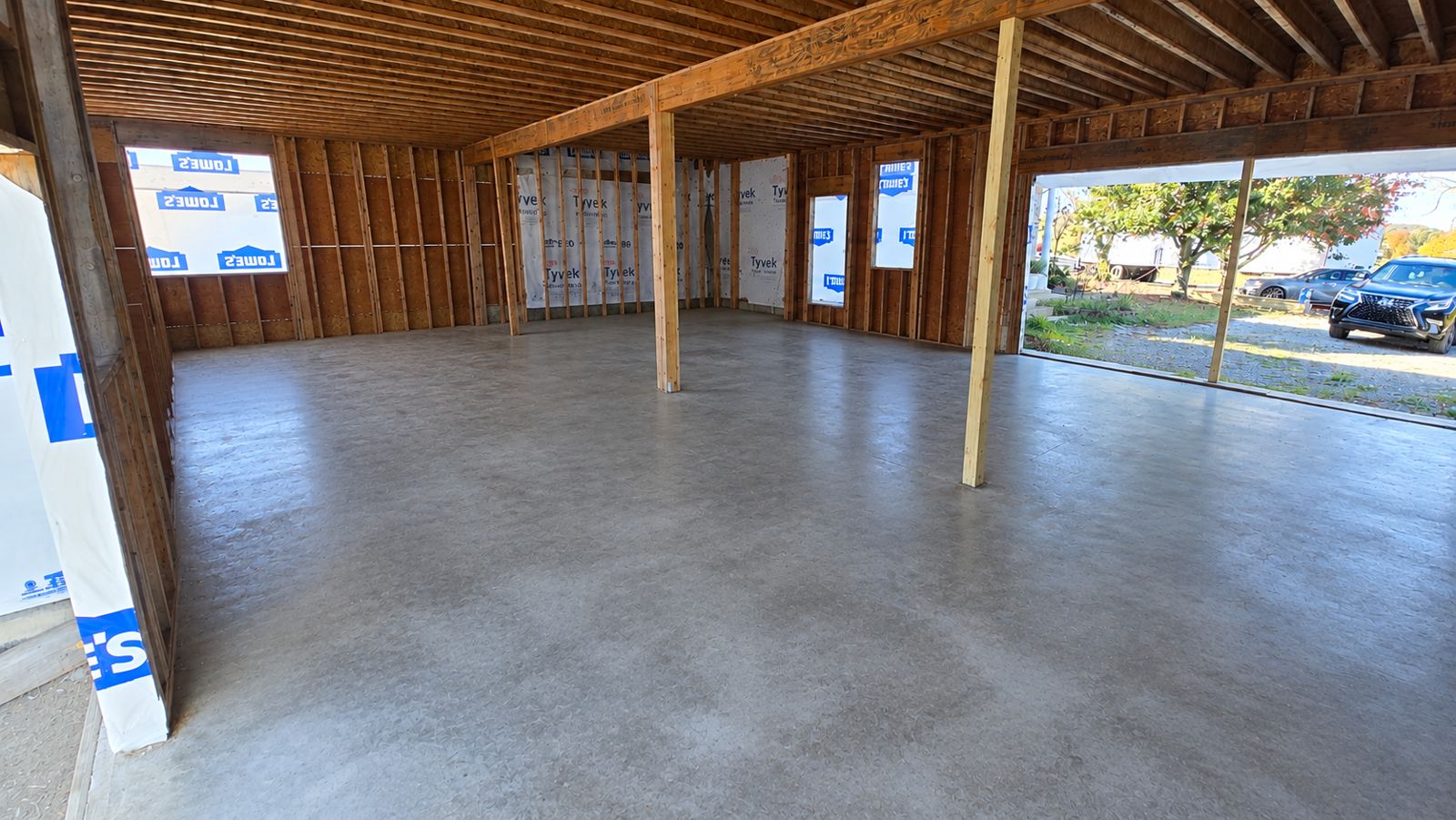 Garage with sheathed exterior walls, window openings, and a smooth concrete floor