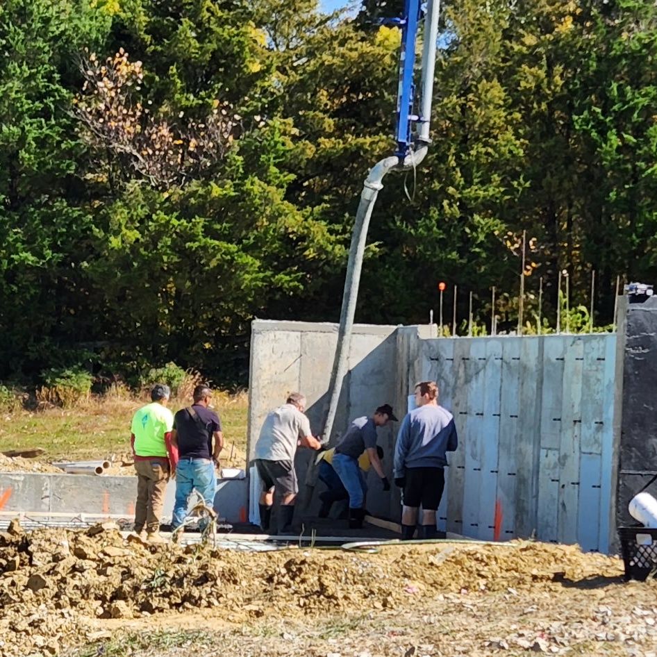Crew placing concrete into foundation wall forms from a pump truck hose